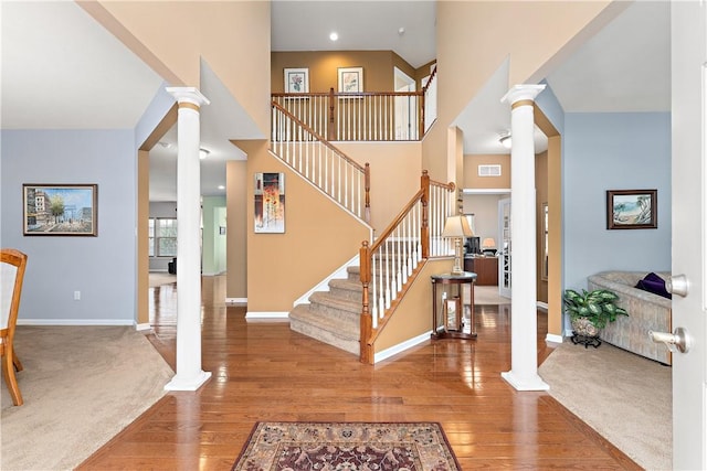 staircase with baseboards, visible vents, ornate columns, and wood finished floors