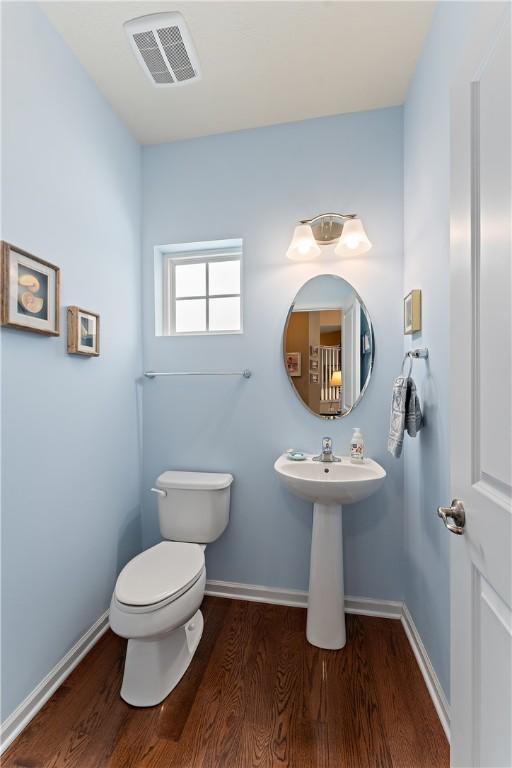 bathroom featuring toilet, baseboards, visible vents, and wood finished floors