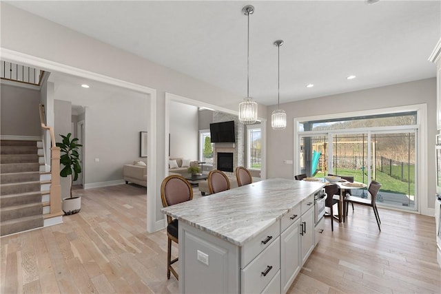 kitchen with light wood finished floors, a kitchen bar, white cabinetry, and decorative light fixtures