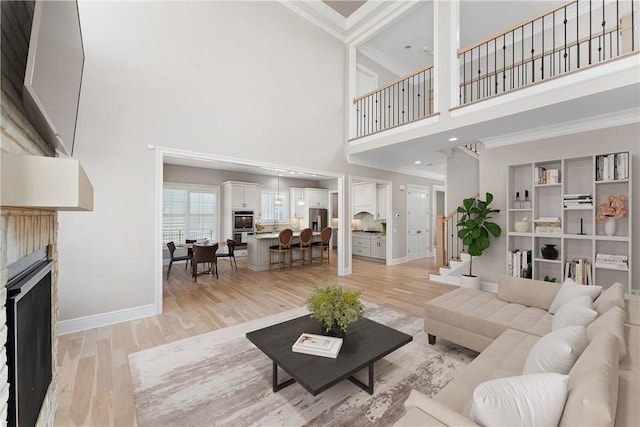 living area featuring light wood finished floors, a fireplace, ornamental molding, and stairway