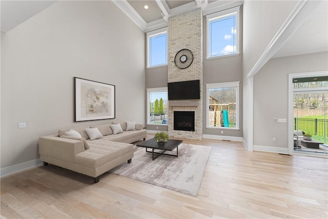 living area featuring a brick fireplace, light wood-style flooring, and baseboards