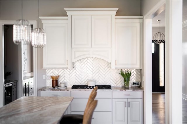 kitchen with tasteful backsplash, gas stovetop, white cabinetry, and an inviting chandelier