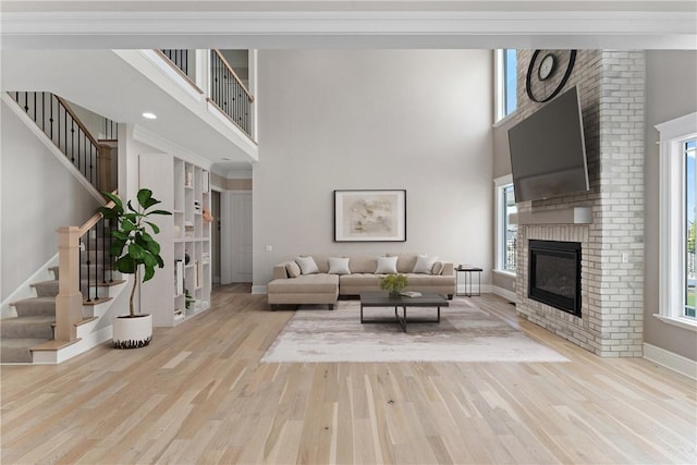 living area featuring a brick fireplace, stairs, a high ceiling, and wood finished floors