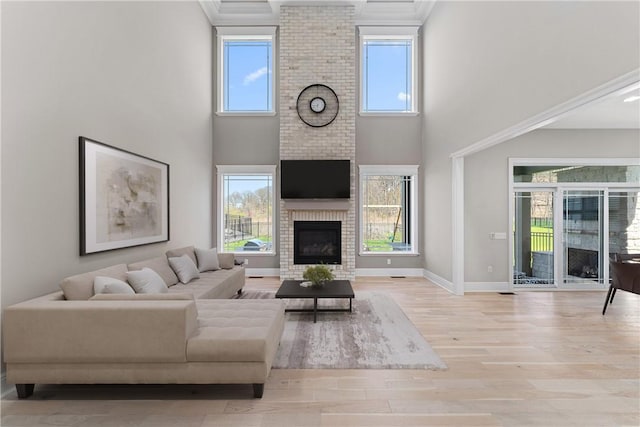 living area with a fireplace, a towering ceiling, baseboards, and wood finished floors