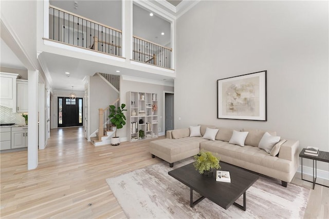 living room featuring recessed lighting, baseboards, ornamental molding, stairway, and light wood-type flooring