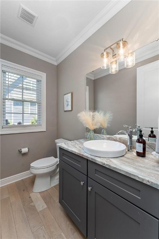 bathroom with ornamental molding, visible vents, toilet, and wood finished floors