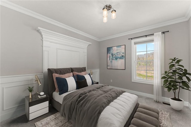 carpeted bedroom with ornamental molding, wainscoting, and baseboards