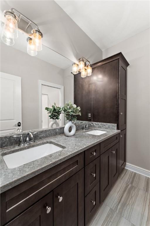 bathroom featuring a sink, baseboards, and double vanity