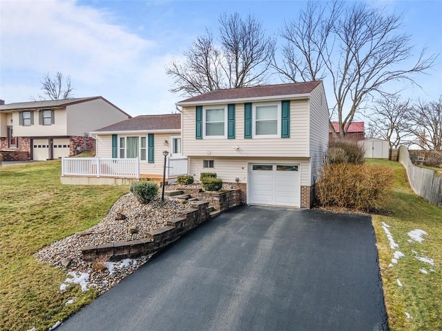 split level home featuring driveway, a front lawn, an attached garage, and brick siding