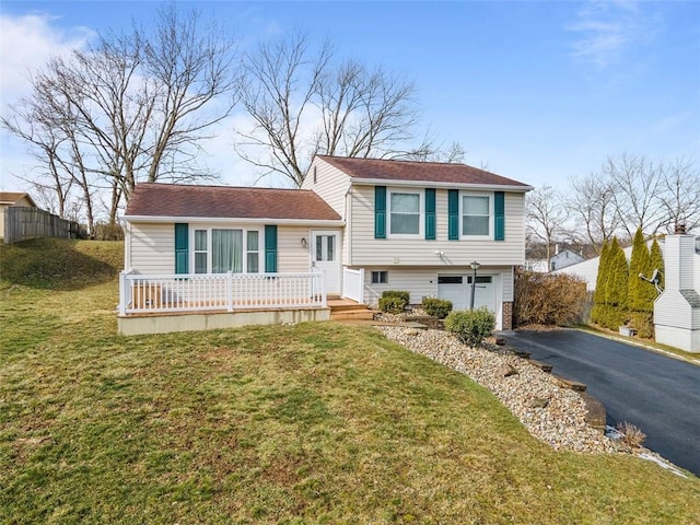 split level home featuring a garage, aphalt driveway, and a front yard