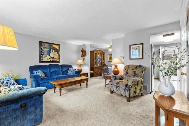 living room with a textured ceiling, visible vents, and carpet flooring