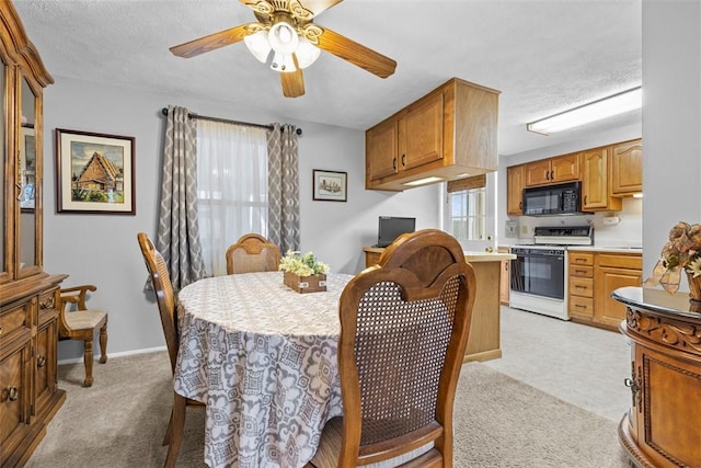 dining room with light carpet, plenty of natural light, a ceiling fan, and baseboards