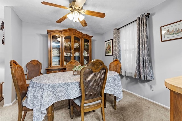 carpeted dining room with ceiling fan and baseboards