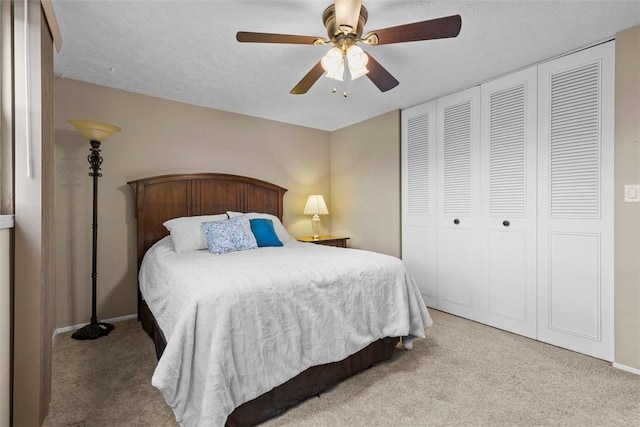 carpeted bedroom with a ceiling fan, a closet, and a textured ceiling