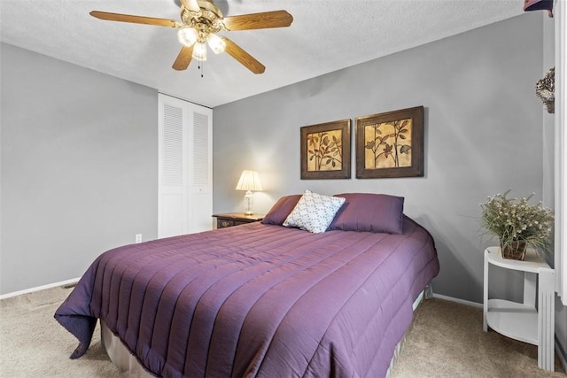 carpeted bedroom with a textured ceiling, a closet, a ceiling fan, and baseboards