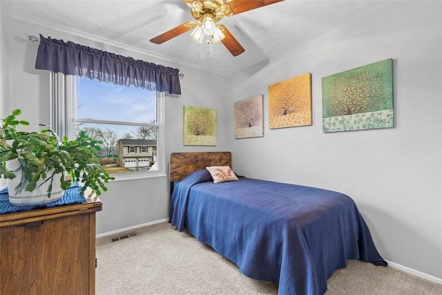 carpeted bedroom with a ceiling fan, visible vents, a textured ceiling, and baseboards