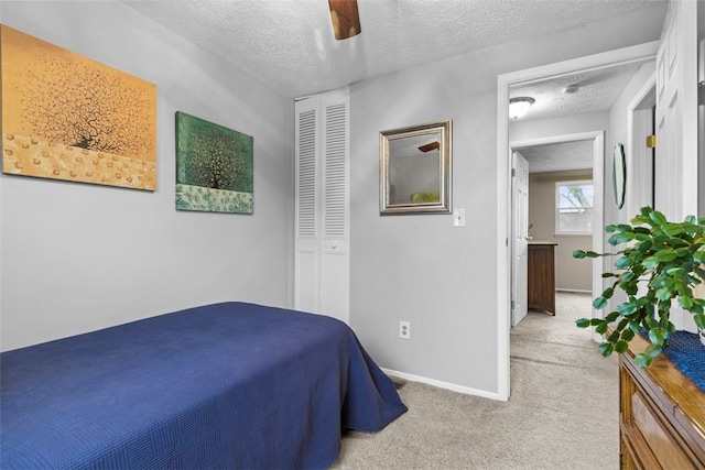 bedroom with a closet, a ceiling fan, carpet flooring, a textured ceiling, and baseboards