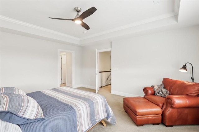 bedroom featuring a raised ceiling, light colored carpet, crown molding, and baseboards