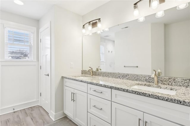 bathroom with double vanity, visible vents, a sink, and wood finished floors