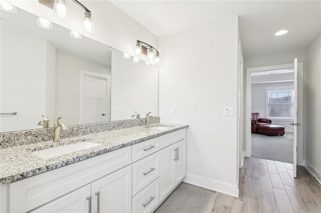 ensuite bathroom with double vanity, baseboards, and a sink