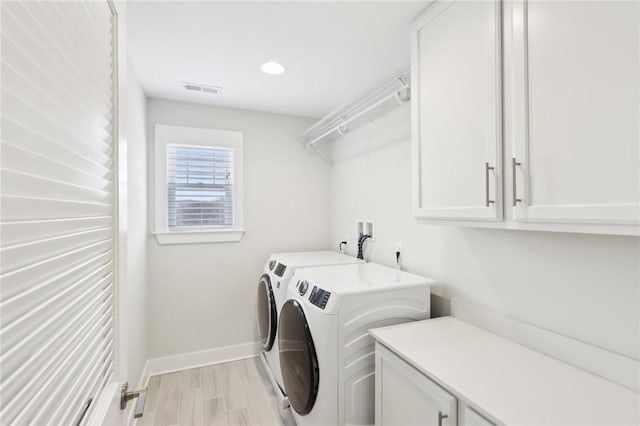 laundry area with cabinet space, light wood finished floors, visible vents, baseboards, and washer and clothes dryer