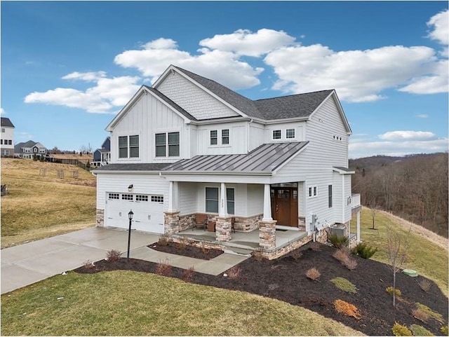 view of front of property with driveway, a garage, stone siding, a standing seam roof, and a porch