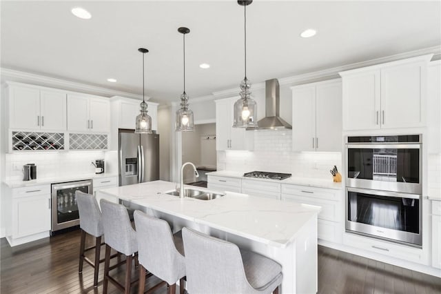 kitchen featuring crown molding, stainless steel appliances, a sink, beverage cooler, and wall chimney exhaust hood