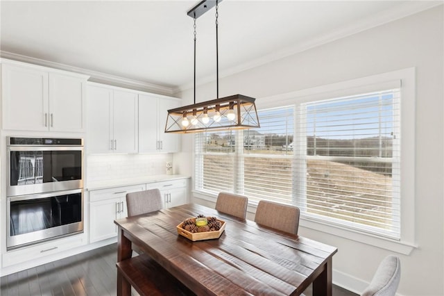 dining area featuring dark wood-style flooring and crown molding