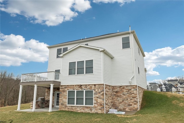 back of property featuring a patio area, stone siding, and a yard