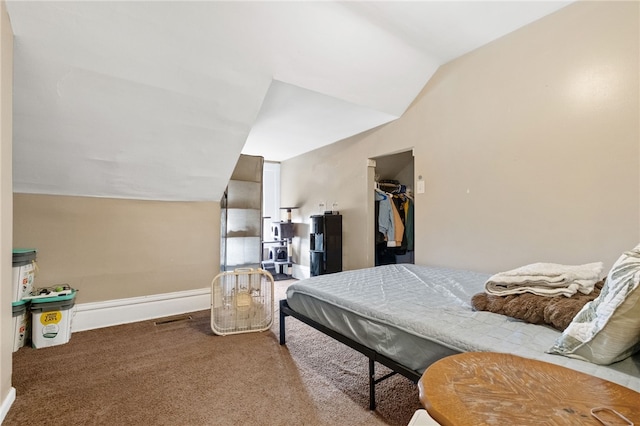 carpeted bedroom with vaulted ceiling, a spacious closet, and baseboards