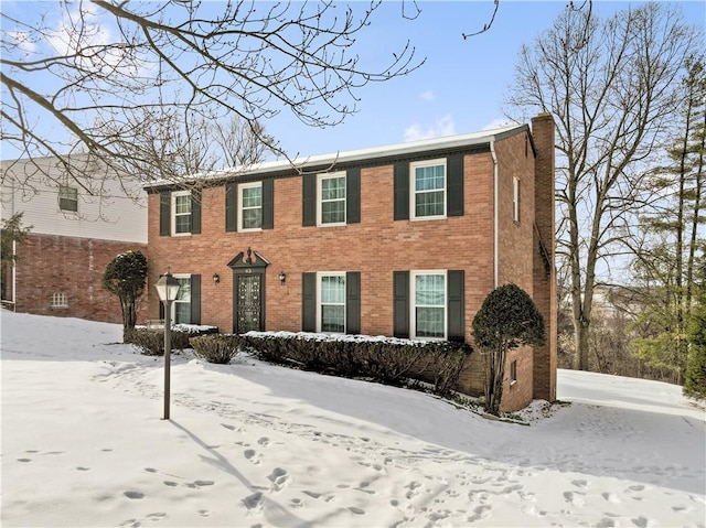 colonial home with brick siding and a chimney