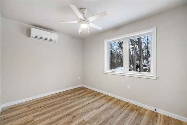 unfurnished room with light wood-style floors, an AC wall unit, ceiling fan, and baseboards