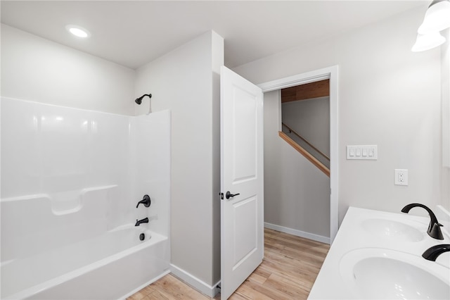 full bath featuring shower / bathtub combination, wood finished floors, a sink, and baseboards