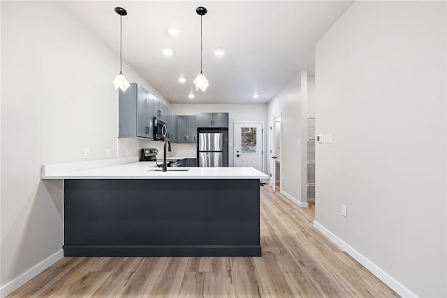 kitchen with stainless steel appliances, light countertops, decorative backsplash, a peninsula, and baseboards