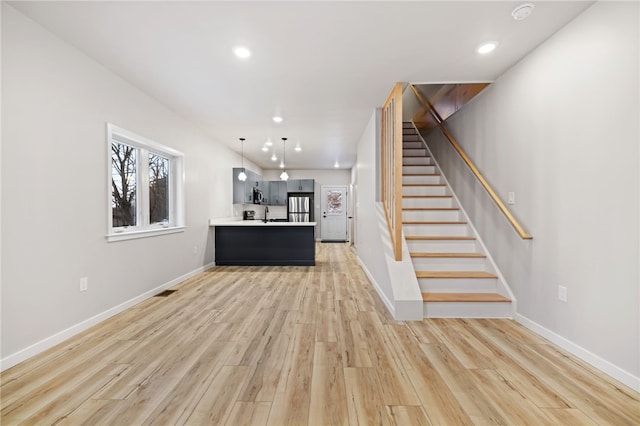 kitchen featuring light wood-type flooring, baseboards, appliances with stainless steel finishes, and light countertops