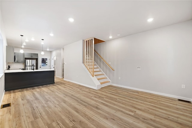 unfurnished living room featuring recessed lighting, visible vents, stairway, light wood-type flooring, and baseboards