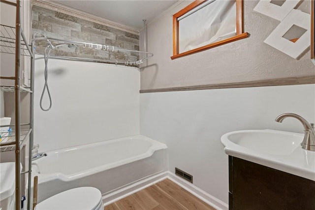 bathroom featuring visible vents, toilet, wood finished floors, vanity, and shower / washtub combination