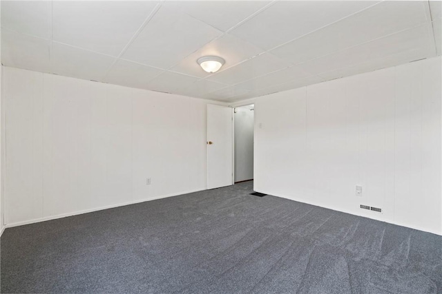 unfurnished room featuring visible vents, dark carpet, and a drop ceiling