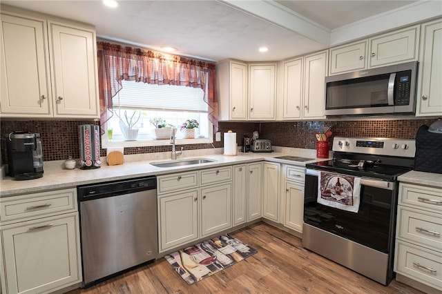 kitchen featuring ornamental molding, light countertops, a sink, stainless steel appliances, and backsplash