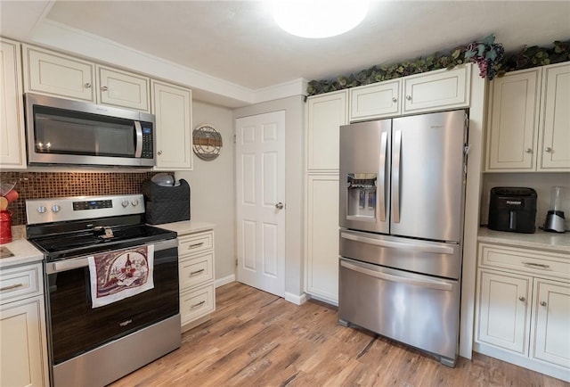 kitchen featuring appliances with stainless steel finishes, light countertops, light wood finished floors, baseboards, and backsplash