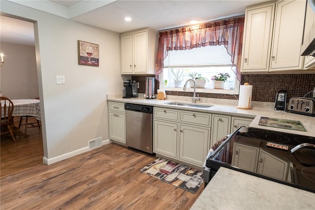 kitchen with tasteful backsplash, light countertops, visible vents, dishwasher, and a sink