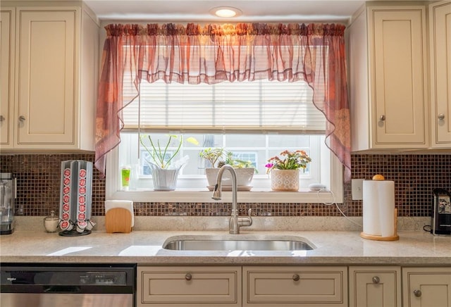 kitchen with a sink, cream cabinets, plenty of natural light, and dishwashing machine