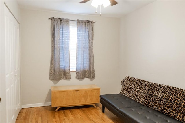 sitting room featuring light wood-type flooring, ceiling fan, and baseboards