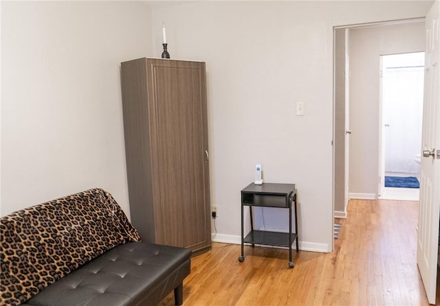 sitting room with baseboards and light wood-type flooring