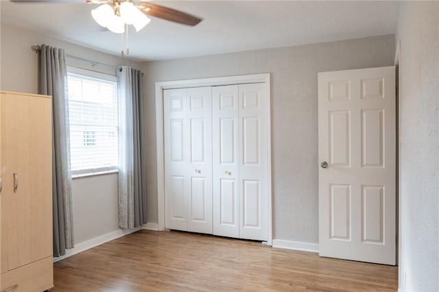 unfurnished bedroom featuring wood finished floors, a closet, a ceiling fan, and baseboards