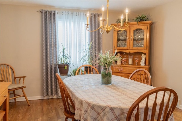 dining area with baseboards, light wood finished floors, and an inviting chandelier
