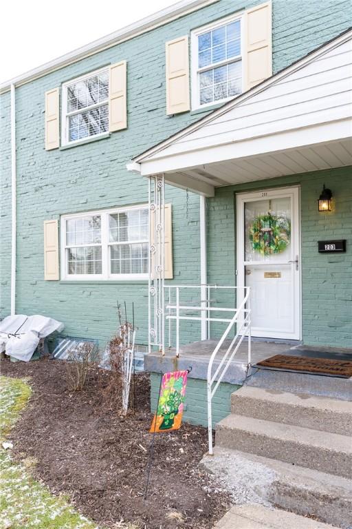 view of exterior entry featuring covered porch and brick siding