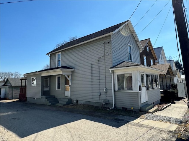 view of side of home featuring crawl space, a sunroom, and entry steps