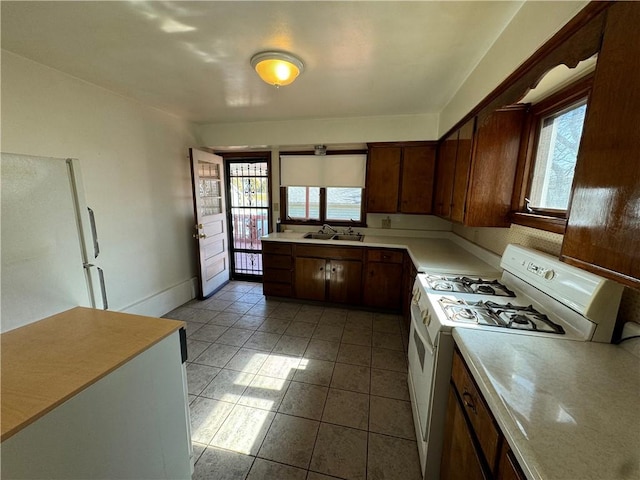 kitchen with light countertops, white appliances, plenty of natural light, and a sink