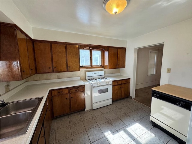 kitchen with light countertops, decorative backsplash, a sink, white appliances, and tile patterned floors